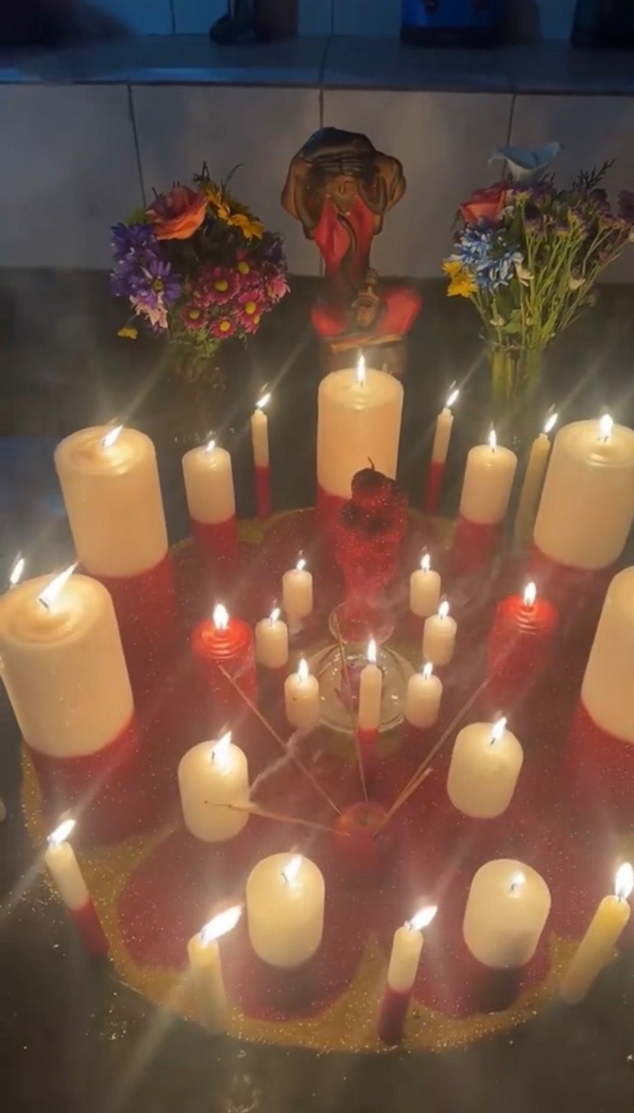 Trabalho amoroso firmado com velas brancas e vermelhas em círculo, maçã ao centro e flores no altar